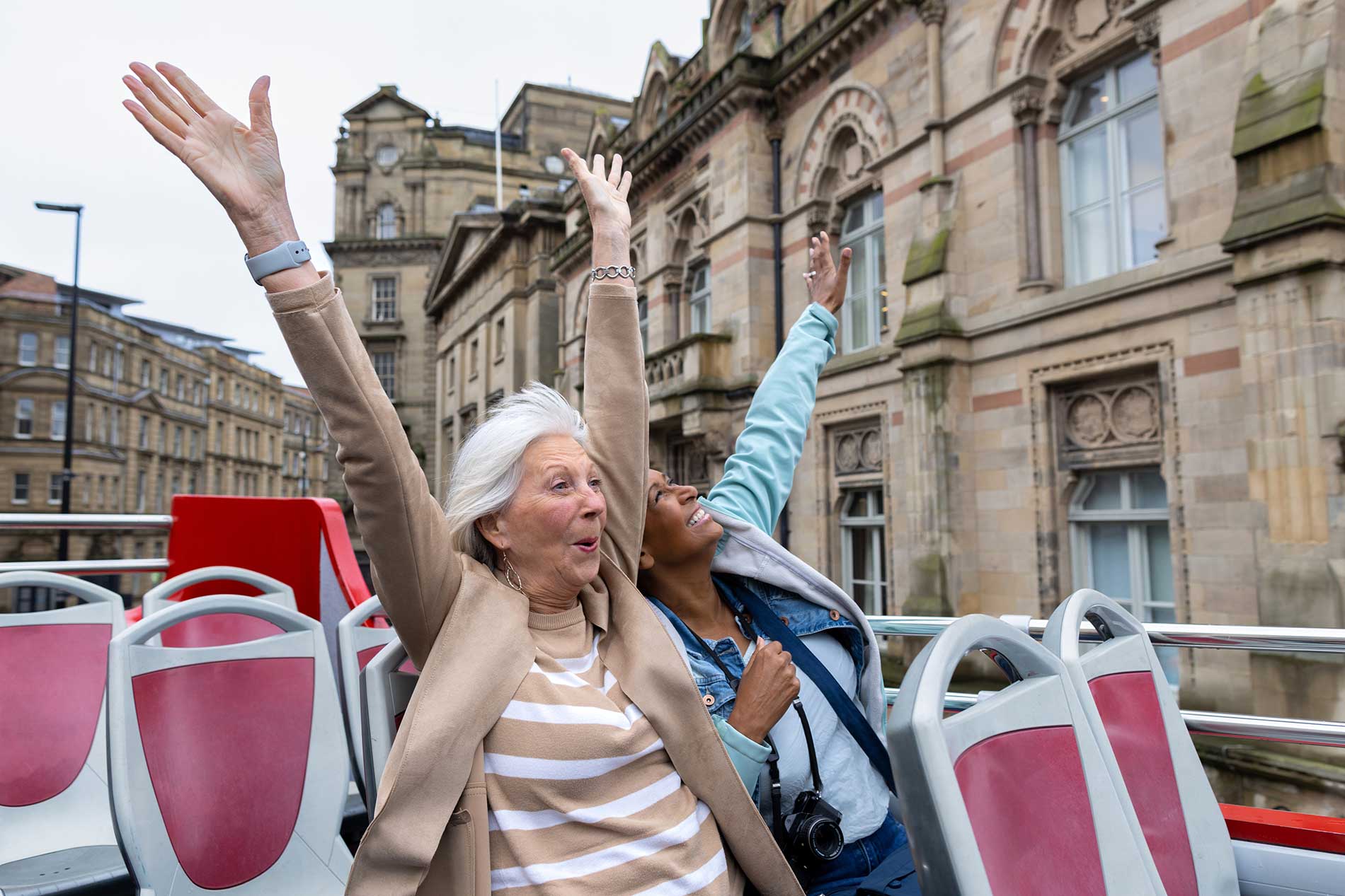Happy travellers on an open-top bus tour in England